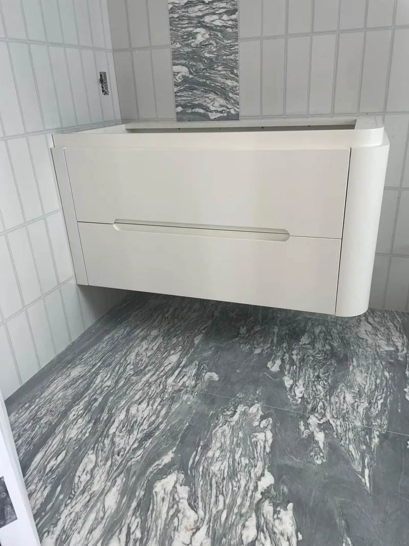 Bathroom with a floating white vanity, a tiled wall, and a marble-patterned tile floor.