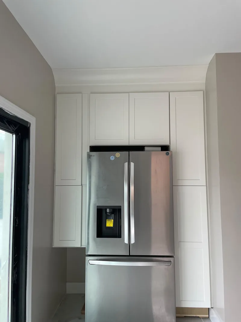 Kitchen with white cabinets, a stainless steel refrigerator, and recessed ceiling lights.
