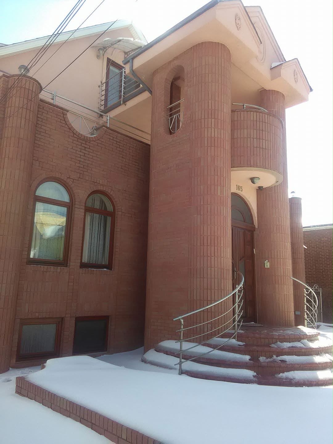 Brick exterior with arched windows, curved brick entry columns, a wood front door, and snow-covered brick steps.